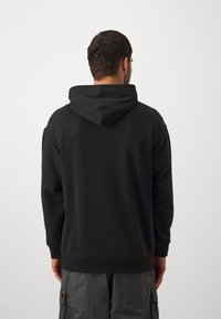Sort hættetrøje med en blød tekstur, ribbede manchetter og kant, der har en hætte med snor. Enkel, klassisk design uden pynt.