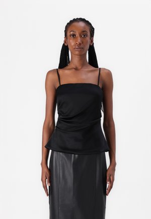 Top in satin nero con spalline sottili, texture drappeggiata e vita aderente. Abbinato a una gonna a tubino in pelle nera.