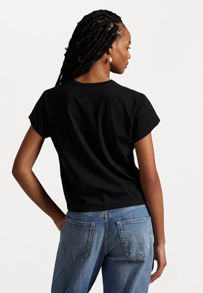 Black cotton t-shirt with short sleeves and a crew neckline, paired with blue denim jeans featuring back pockets and a faded look.