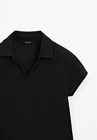 Polo noir avec un col V, à manches courtes, fabriqué à partir d'un tissu lisse et léger. Présente des détails de couture minimaux.