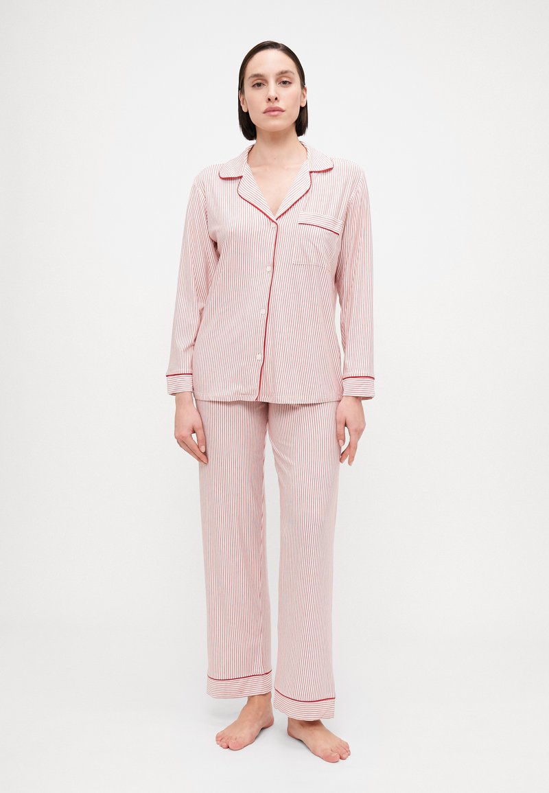 Conjunto de pijama riscado em vermelho e branco, com mangas longas, uma blusa de botão com um bolso e calças correspondentes com bainhas ajustadas.