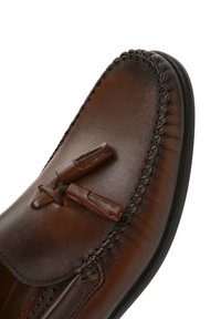 I mocassini in pelle marrone presentano un design cucito con nappine e una texture liscia, punta arrotondata e suola in gomma per una migliore aderenza.