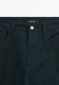 Tmavě zelené bavlněné kalhoty s předním zapínáním na knoflík, prošívanými detaily a štítkem s nápisem "Massimo Dutti" na pase.