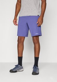 Purple shorts made of lightweight fabric, featuring a logo on the left leg, paired with gray shoes and dark socks.