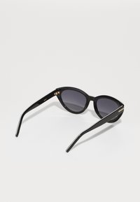 Mustad musta värvi cat-eye päikeseprillid hallide läätsedega. Läbipaistva plastraami, kitsaste kätega, mis on kaunistatud kuldsete detailidega. Minimalistlik disain ilma mustriteta.