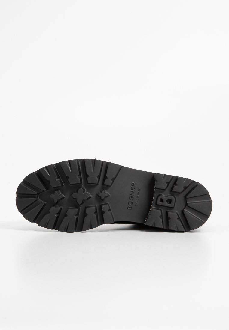 Schwarze Gummisohle mit tiefen Rillen, gekennzeichnet mit "BOGNER." Das Design weist eine gemusterte Textur mit ausgeprägten Traktionselementen für besseren Halt auf.
