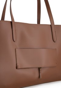 Brown leather tote bag with smooth texture, minimalistic design, dual handles, and a front pocket secured by a flap.
