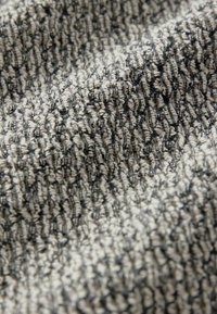 Tissu texturé aux couleurs gris et crème, présentant un motif tissé avec des fibres en relief et un léger éclat, mettant en valeur la profondeur et la qualité tactile.