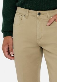 Pantalones caqui de corte ajustado, con cremallera y diseño de cinco bolsillos. Fabricados en una mezcla de algodón suave y duradera.