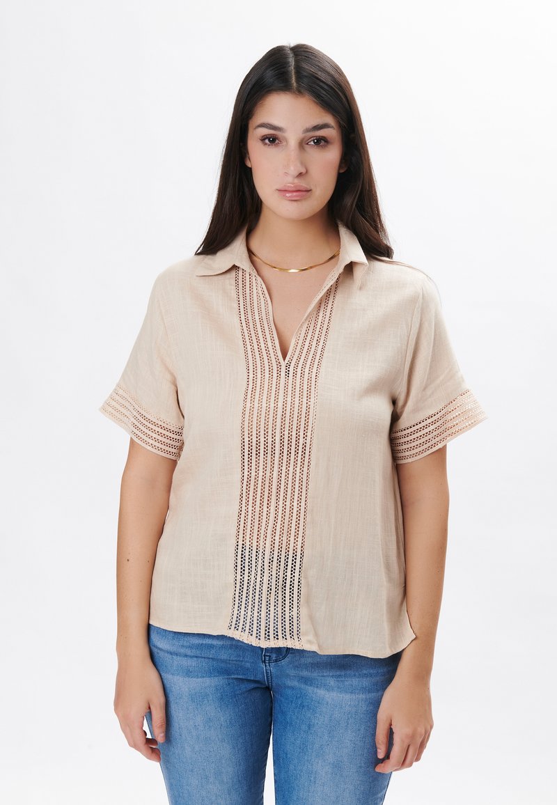 Camisa de lino beige claro con mangas cortas, escote en V y un intrincado detalle en patrón a lo largo del centro y en los puños.