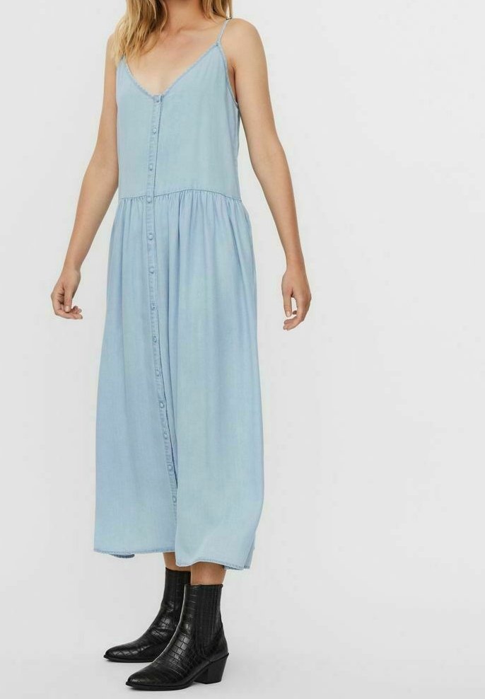 Vaaleansininen farkku-maksimekko ohuilla olkaimilla ja napitettavalla etuosalla, jossa on levenevä helma ja polven pituinen vaippa, yhdistettynä mustiin nilkka-bootseihin.