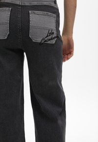 Grijze denim broek met een donkerdere wassing, twee achterzakken met een logo "Lola Casademunt" in het zwart en een relaxed fit ontwerp.