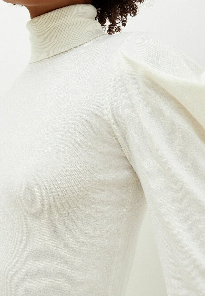 Maglione a collo alto in tessuto leggero, con corpo aderente e maniche puff, caratterizzato da una texture a coste e una finitura liscia.