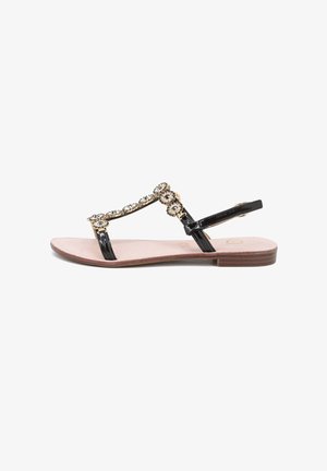 Sandal in pelle verniciata nera con decorazioni in oro e cristalli, suola piatta, design con fascia a T e soletta imbottita beige.