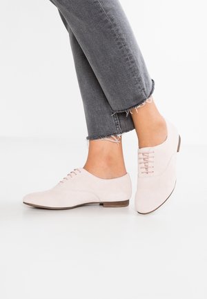 Lichtroze suède schoenen met een lage hak en veters, gecombineerd met gecropte grijze jeans met rafelige zomen.