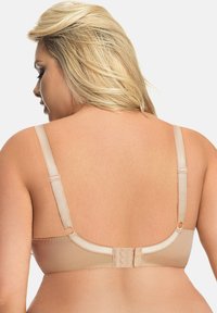 Beige bh met verstelbare bandjes, haak- en oogsluiting en een gladde textuur. Heeft golfvormige randen en een minimalistisch ontwerp voor ondersteuning.