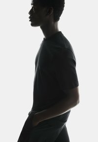 Black short-sleeve t-shirt featuring a crew neckline and a smooth, soft texture, displayed on a silhouette against a light background.