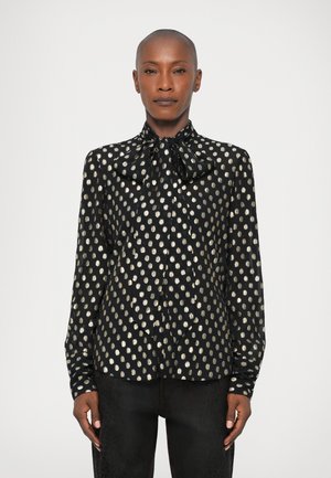 Schwarze Bluse mit goldenen ovalen Punkten, die über einen Schleifenkragen und lange Ärmel verfügt. Glattes Material mit taillierter Passform.