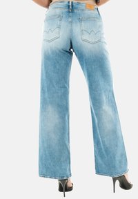 Jeans de corte ancho en un azul claro, fabricados en denim, con una textura desvaída, dos bolsillos traseros con costuras curvas y una etiqueta de cuero en la cinturilla.