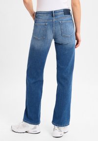 Blaue Denim-Jeans mit geradem Schnitt, ausgestattet mit einem mittelhohen Bund und zwei Gesäßtaschen. Der Stoff hat einen leicht verblassten Look.