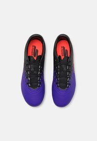 Purple and black athletic shoes with a smooth texture, featuring laces, a vibrant red interior, and a splattered pattern on the sides.