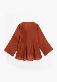Rustfarvet bluse med trekvart lange klokkeærmer, der har vertikale pyntesyninger langs ryggen, lavet af letvægtsstof.