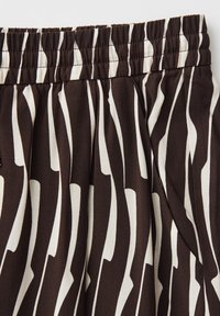 Tessuto a righe zebrate marrone e bianco con vita elastica e tasca visibile sulla cucitura laterale.