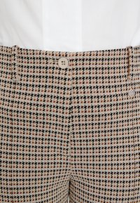 Herren-Hosen mit Muster im Fischgrätenmuster in Schwarz, Beige und Rostbraun, mit einem Knopfverschluss und dezenten Taschen. 