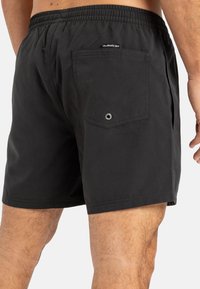 Schwarze Badeshorts mit einem elastischen Bund, einer Gesäßtasche und einem kleinen Logosticker in der Nähe des Bundes. Glattes, leichtes Gewebe.
