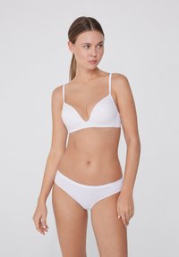 Sostenitore bianco e culotte abbinate realizzati in materiale liscio e elastico. Il reggiseno ha una scollatura profonda e spalline sottili e regolabili.