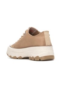 Zapatillas de ante beige con cordones, suela blanca gruesa, panel lateral texturizado y lengüeta acolchada. Presenta acentos de goma para mayor tracción.