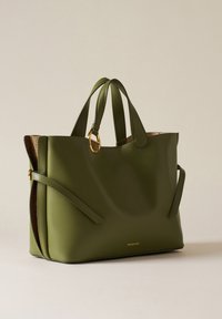 Green leather tote bag with dual handles, textured side accent, gold hardware ring, and embossed logo on the front. Smooth finish.