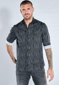 Schwarz-weiß gestreiftes Hemd mit Knopfleiste und hochgekrempelten Ärmeln, aus leichtem Stoff, mit tailliertem Schnitt und dezentem Logodetail.