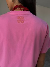 T-shirt di cotone rosa con un design decorativo ricamato in oro sulla parte superiore della schiena. Maniche corte e vestibilità rilassata.