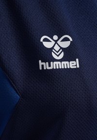 Marineblauwe sporttrui van gemêleerd meshweefsel, met een wit hummel-logo voorzien van een bijontwerp en geometrische accenten.