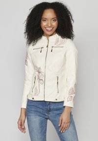 Veste en simili cuir crème avec des motifs floraux brodés en bordeaux, dotée de poches à fermeture éclair dorées et d'un col montant.