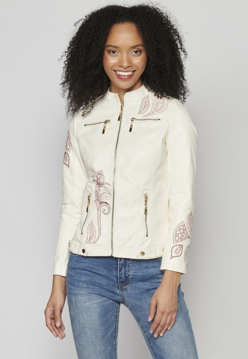 Veste en simili cuir crème avec des motifs floraux brodés en bordeaux, dotée de poches à fermeture éclair dorées et d'un col montant.
