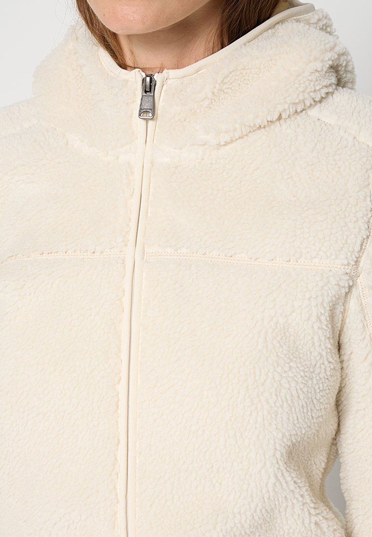 Femme portant une veste en polaire texturée de couleur crème, avec une capuche et une fermeture éclair à l'avant, montrée de la nuque à la taille.