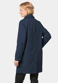 Navy trench coat featuring a classic collar, long sleeves, and snap button accents; smooth texture with a tailored, structured fit.