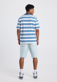 Men's short-sleeve striped shirt in white and blue, paired with light blue denim shorts. Features a classic collar and relaxed fit.