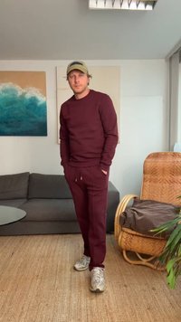 Sweatshirt e calças de jogging em burgundy, feitos de um tecido suave, com punhos elásticos e cintura com cordão, combinados com ténis cinza-claro.