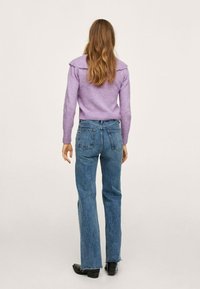 Maglione a maglia lavanda con colletto a coste abbinato a jeans blu a vita alta. I jeans hanno una gamba dritta e orli sfrangiati.