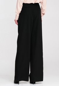 Czarne szerokie spodnie z wysokim stanem, z bocznymi kieszeniami. Gładki materiał z prostym, minimalistycznym wzornictwem.