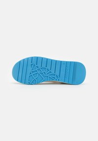 Semelle de chaussure beige clair en matériau gomme bleu. Présente des rainures horizontales et un motif géométrique pour un design antidérapant.