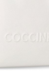 Sacchetto in pelle bianca con testo embossato "COCCINE", texture liscia, design minimalista e sottile motivo a grana.