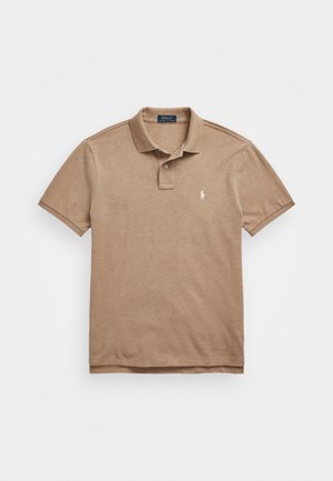 Polo shirt marron en tissu doux, avec une patte de boutonnage à trois boutons, des manches courtes et un petit logo brodé sur la poitrine gauche.