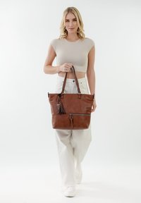 Borsa a tracolla in pelle marrone con scomparto con zip, dettaglio con frange e doppio manico, caratterizzata da una texture liscia e una forma strutturata.