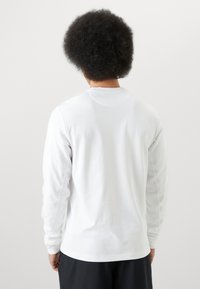 Langærmet hvid skjorte i bomuld med rund halsudskæring og afslappet pasform. Glat tekstur med minimale syningsdetaljer.