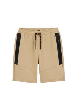 Béžové šortky s elastickým pásom, čiernou šnúrkou a čiernymi zvislými vreckami so zipsom na každej strane.
