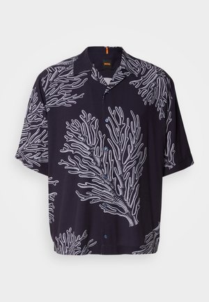 Kortermet, svart skjorte med hvite korall-lignende mønstre, knappestolpe foran og spiss krage. Myk stoff med avslappet passform.